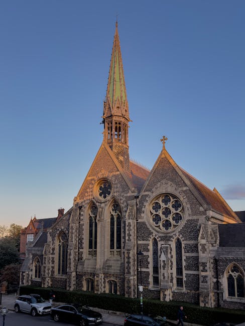 The image depicts the front of a historic brick building with a symmetrical facade featuring large lancet windows with stone tracery and decorative brickwork. A set of stone steps leads up to a wooden